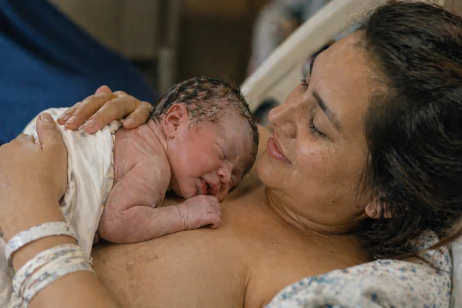 Madre sosteniendo a su bebé recién nacido en contacto piel con piel, representando el bonding y el vínculo afectivo desde el nacimiento. La escena muestra apego seguro, contacto emocional, cuidado materno y la importancia del contacto físico en el desarrollo psicológico y emocional del bebé.